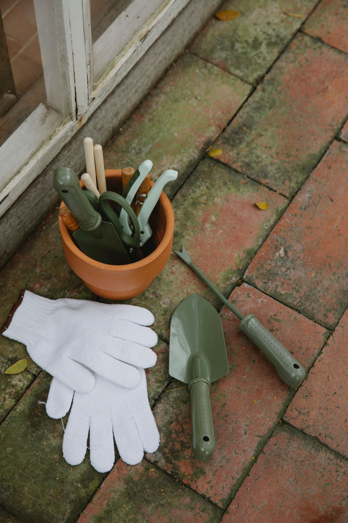 Garden gloves and hand tools laid out on a brick path