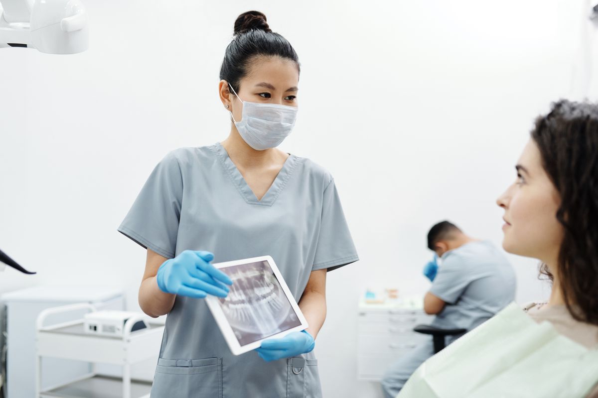 A hygienist showing a patient her X-rays on a tablet