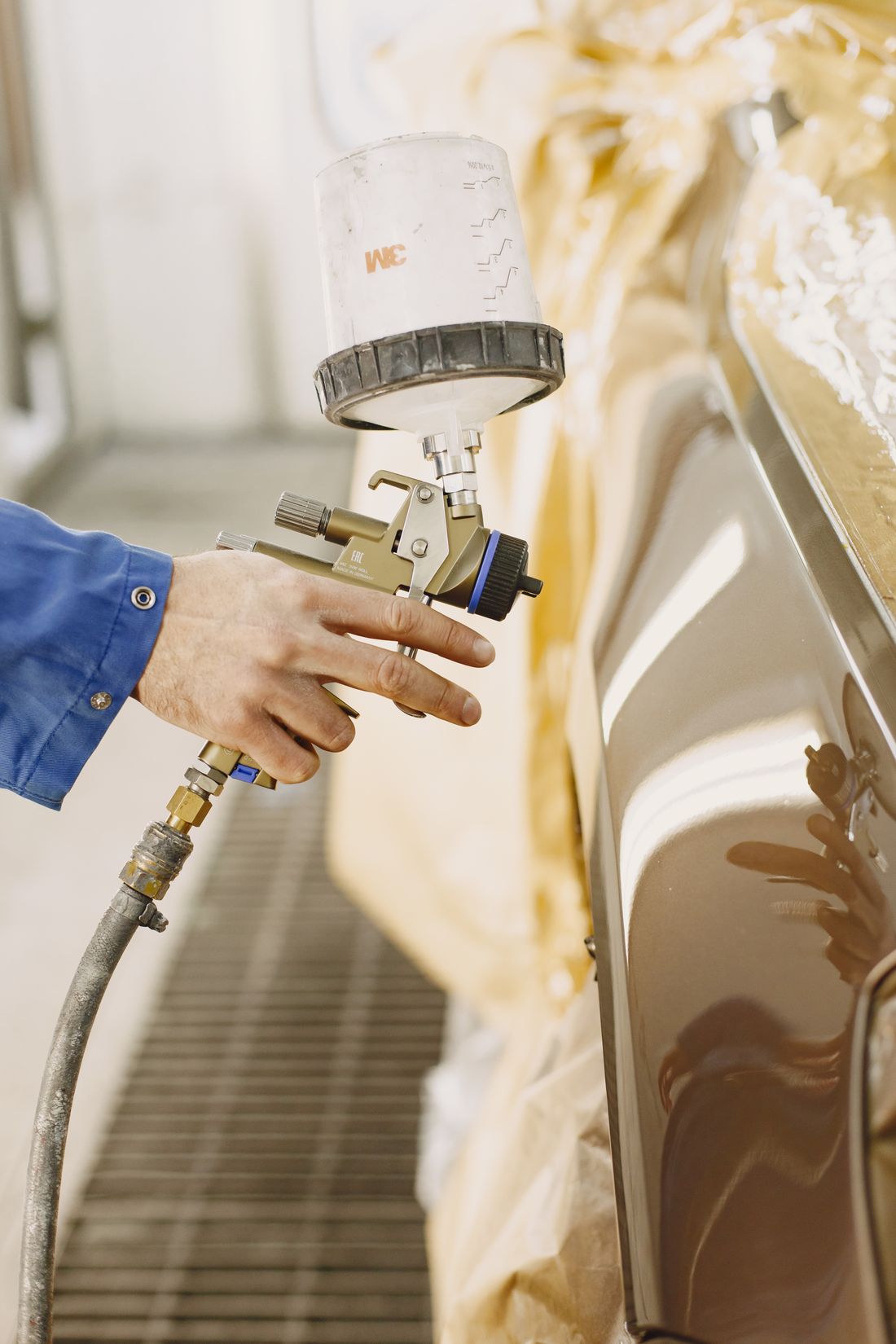 A technician refinishing a panel in the paint bay