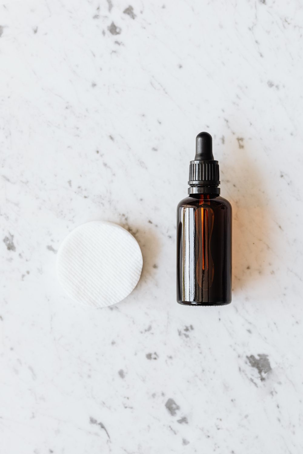 A cotton pad beside a small bottle of essence